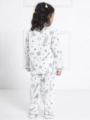 Child wearing a white pajama set with black patterns on a white background