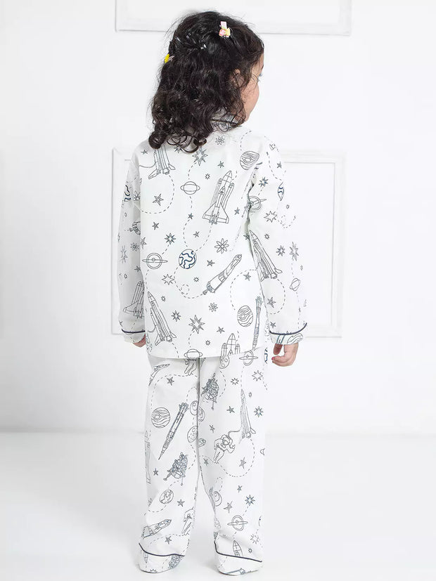 Child wearing a white pajama set with black patterns on a white background