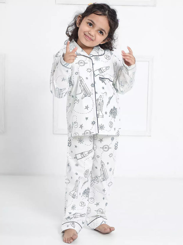 Child wearing a white pajama set with black patterns on a white background