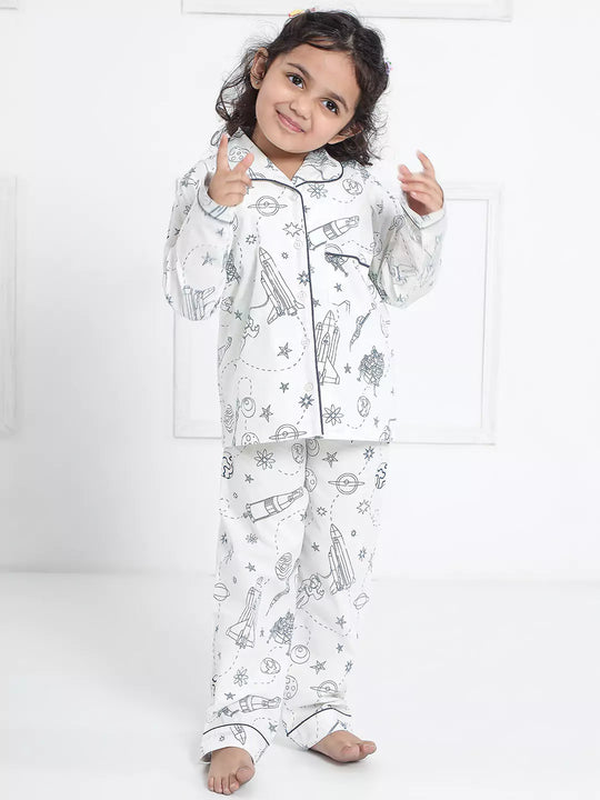 Child wearing a white pajama set with black patterns on a white background