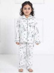 Child wearing a white pajama set with space-themed prints on a white background