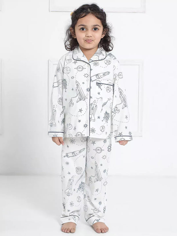 Child wearing a white pajama set with space-themed prints on a white background